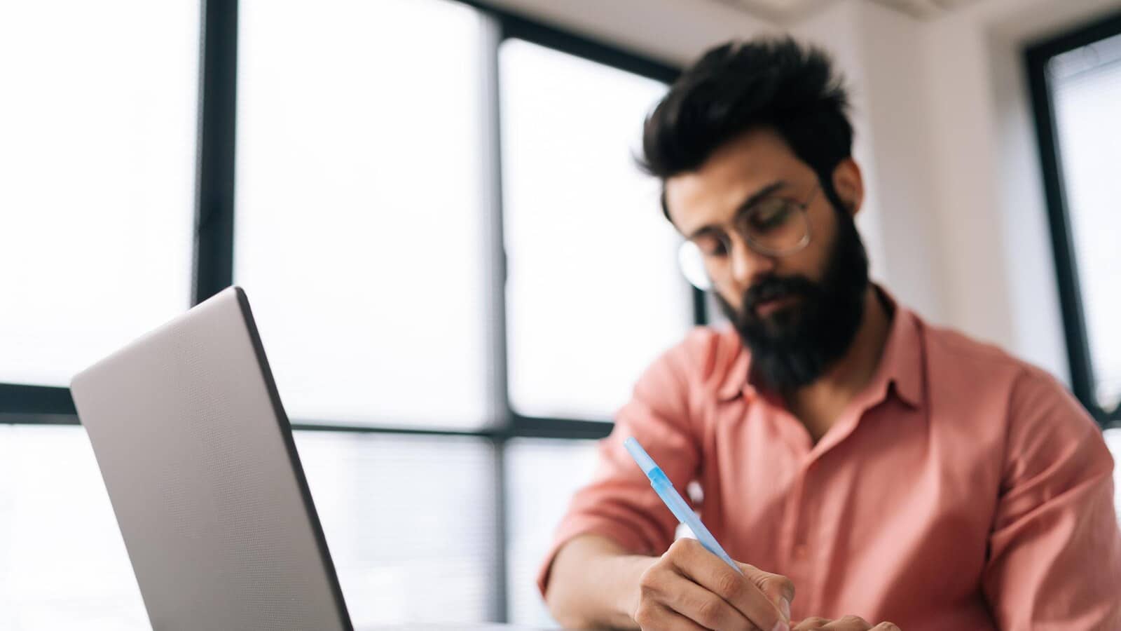 Young Indian entrepreneur planning a business idea with laptop and notebook at home